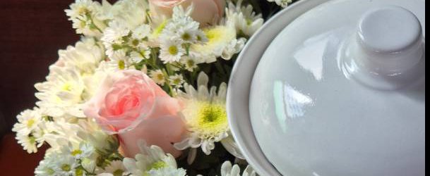 Fresh white and pink flowers beside a white memorial urn